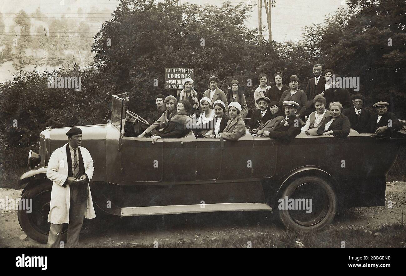 Vintage photo showing a group of tourists in 1931 in an oldtimer convertible bus on a visit in Lourdes, doing a day excursion from Cauterets, ready fo Stock Photo