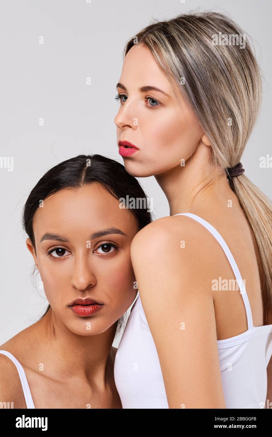Cute caucasian and african girl models with different types of skin leaning to each other Stock Photo