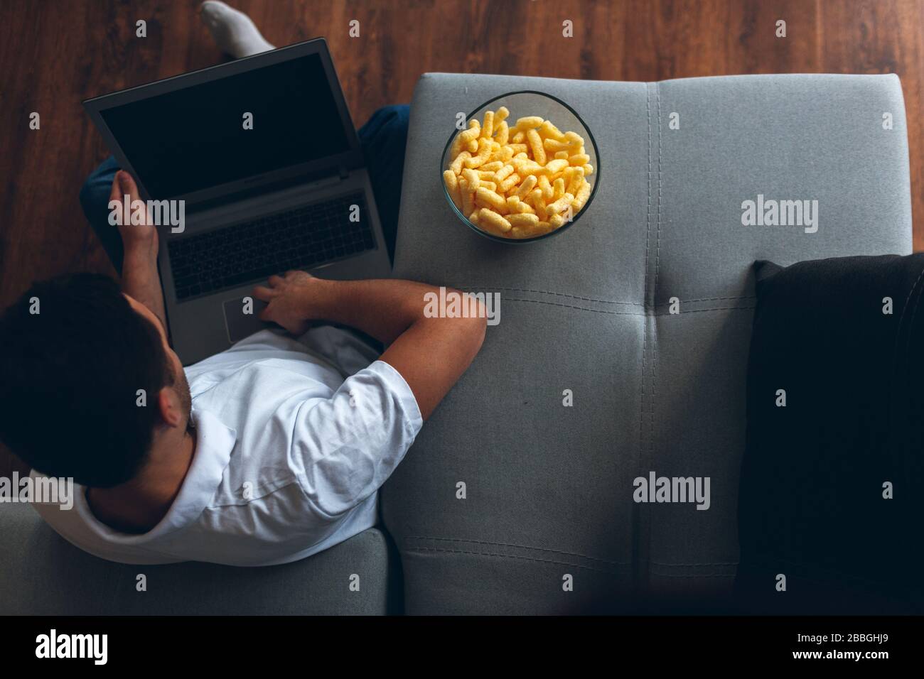 Young man watch tv in his own apartment. Sit alone on floor with legs  crossed and hold laptop on it. Watching movie, sports program. Entertain  himself Stock Photo - Alamy