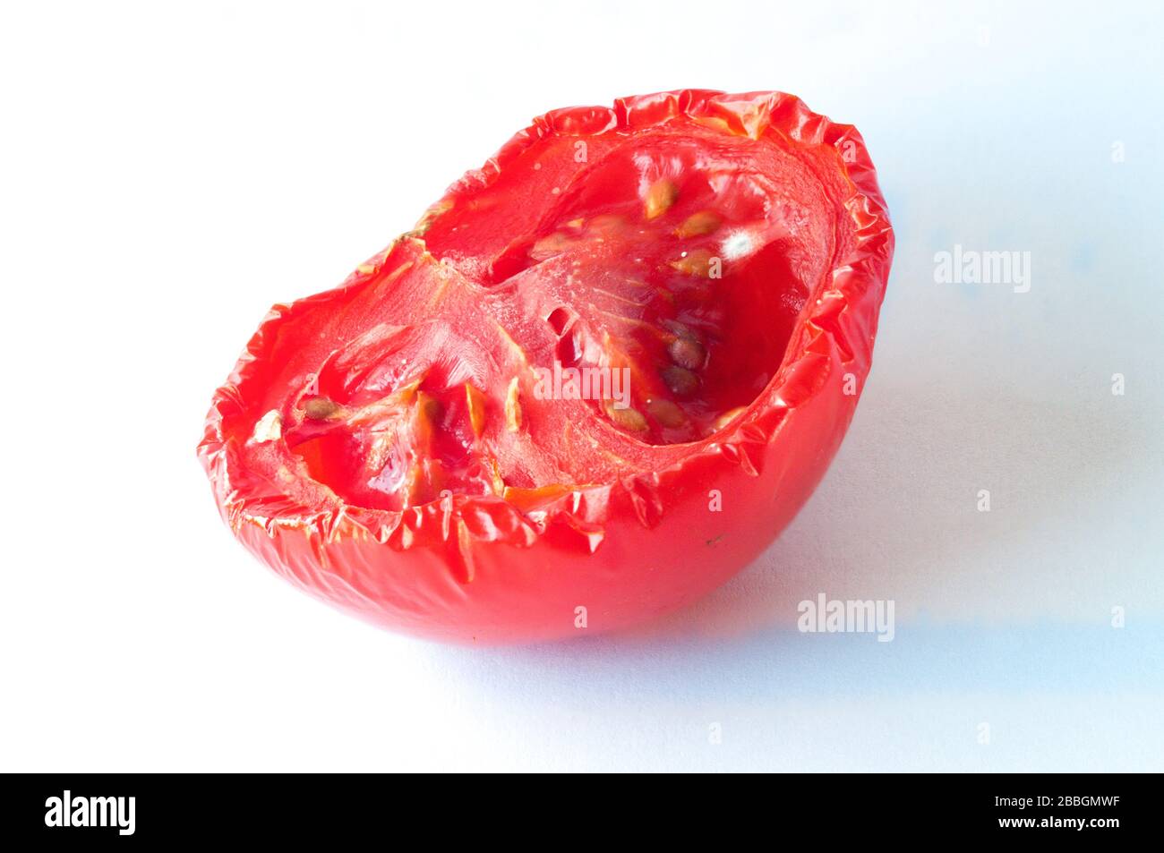 Half of a rotten tomato with the beginning of mould growth. Stock Photo
