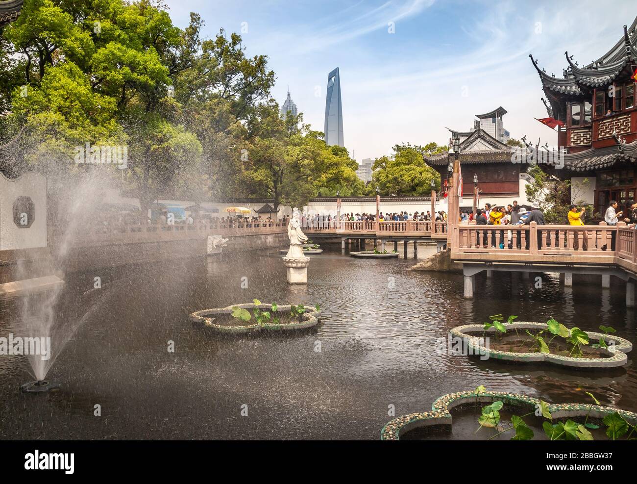Shanghai, China - May 4, 2010: Yu garden off Yuyuan shopping streets. Landscape, statue of goddess Guanyin in pond with green foliage and SWFC and Jin Stock Photo