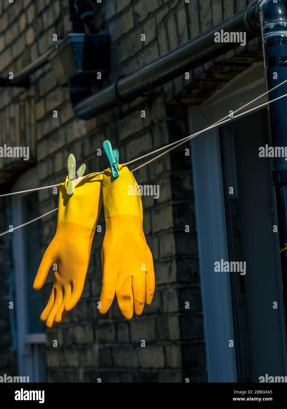 A pair of yellow marigold protective rubber gloves pegged on a clothes line Stock Photo