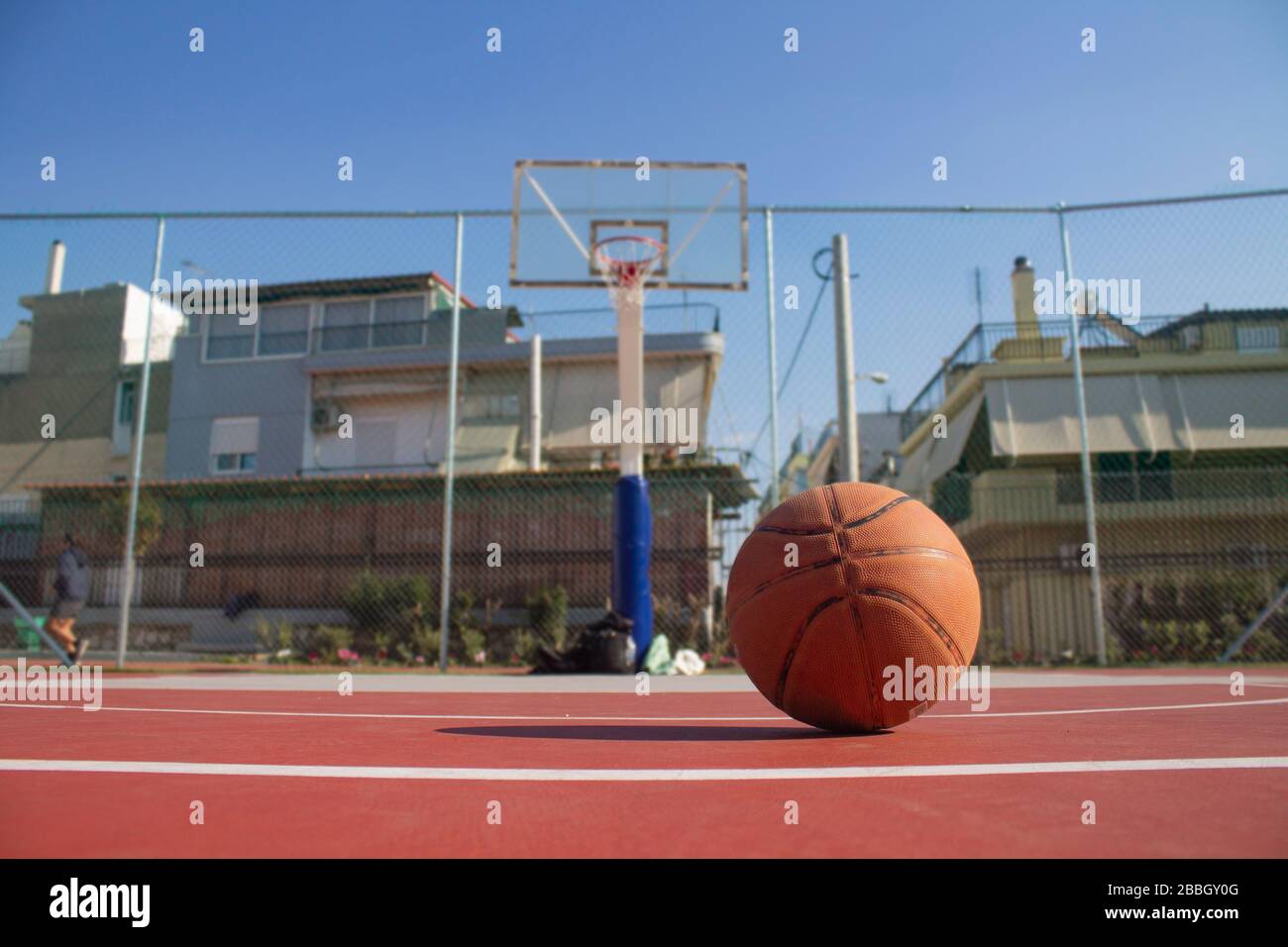 Used basketball in the foreground lies on a basketball court and a  basketball basket with a blurred background Stock Photo - Alamy