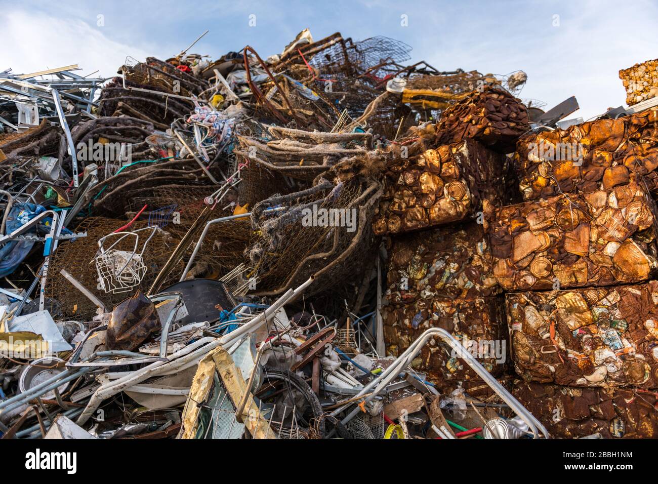 Cubes of rusty cans pressed and stacked next to other scrap in a scrap