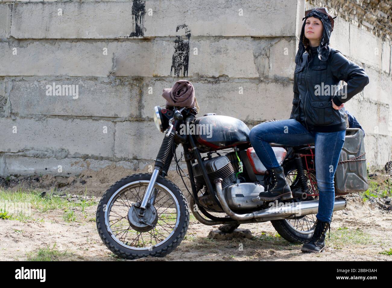 A post apocalyptic woman near motorcycle near destroyed building Stock Photo