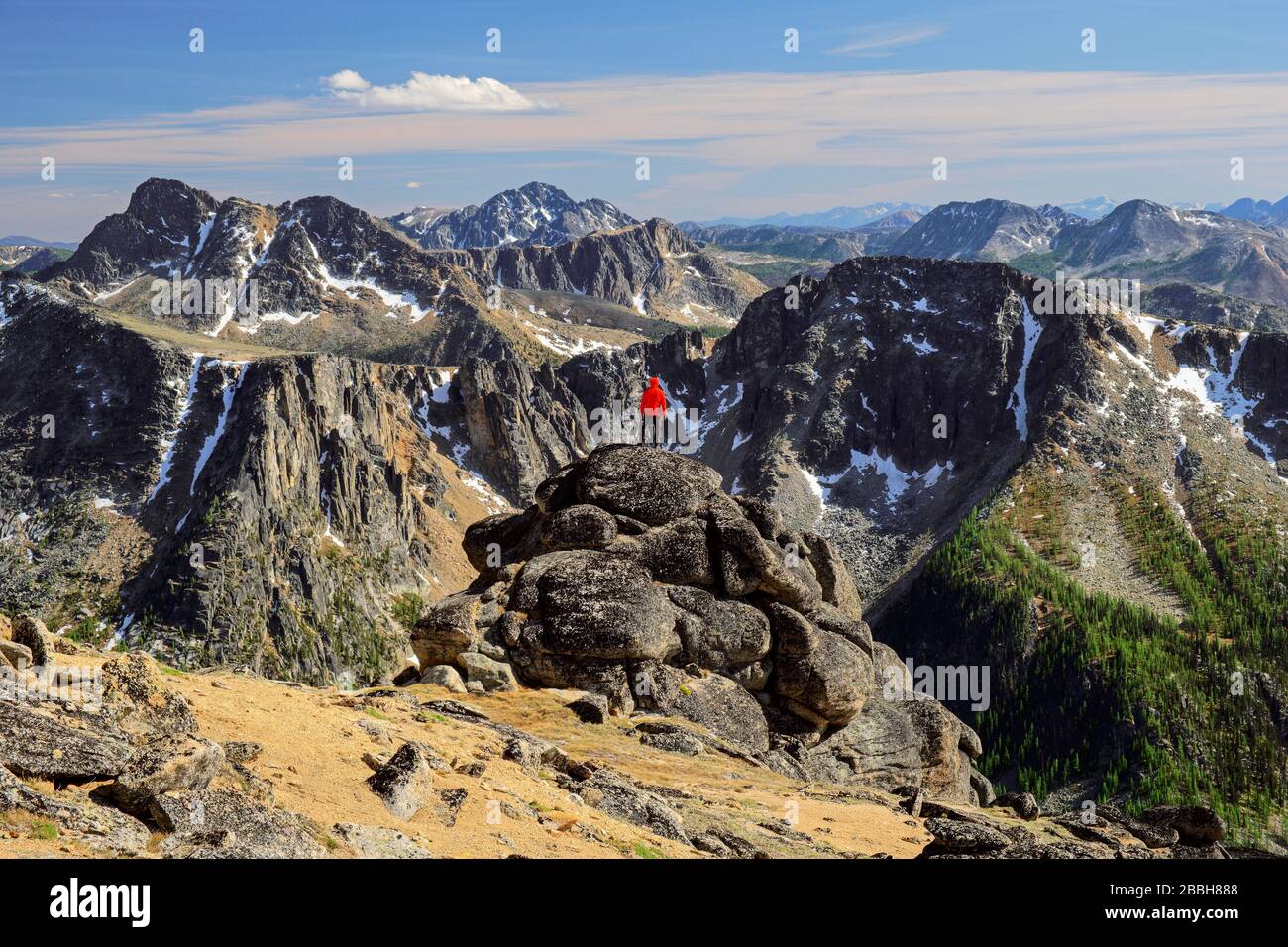 Hiker standing on boulders looking at the North Cascade Mountains, Cathedral provincial park, British Columbia, Canada. Stock Photo