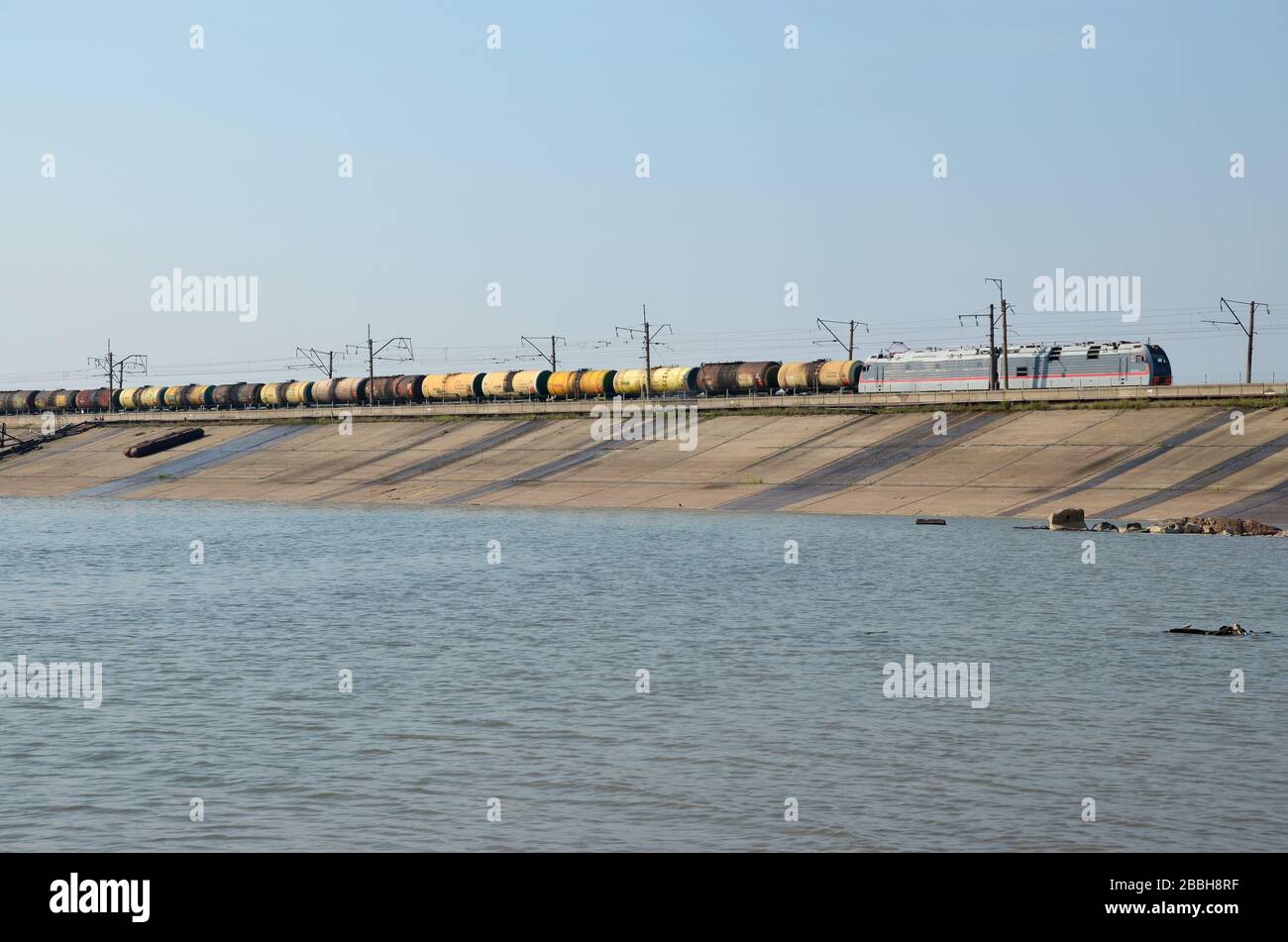 An electrical locomotive with oil tanker wagons on the hydroelectric dam of Bratsk, Russia. This the BAM railway line, Baikal Amour Magistral. Stock Photo