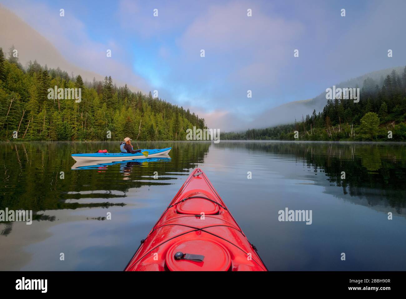 Kayakers with red and blue kayaks on Echo Lake at sunrise, Echo Lake provincial park near Lumby, British Columbia, Canada Stock Photo