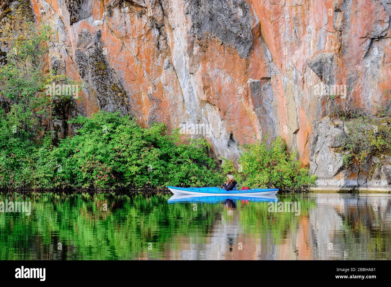 Kayaker with blue kayak looking at rock formations on Yellow Lake in the Okangan Valley of British Columbia, Canada. Stock Photo