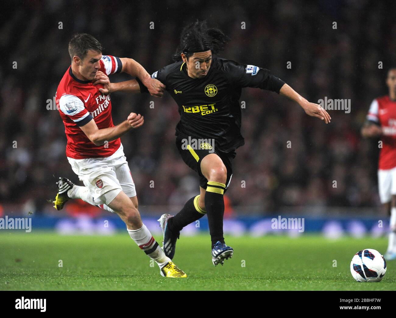 Arsenal's Aaron Ramsey (left) and Wigan Athletic's Roger Espinoza (right) battle for the ball. Stock Photo