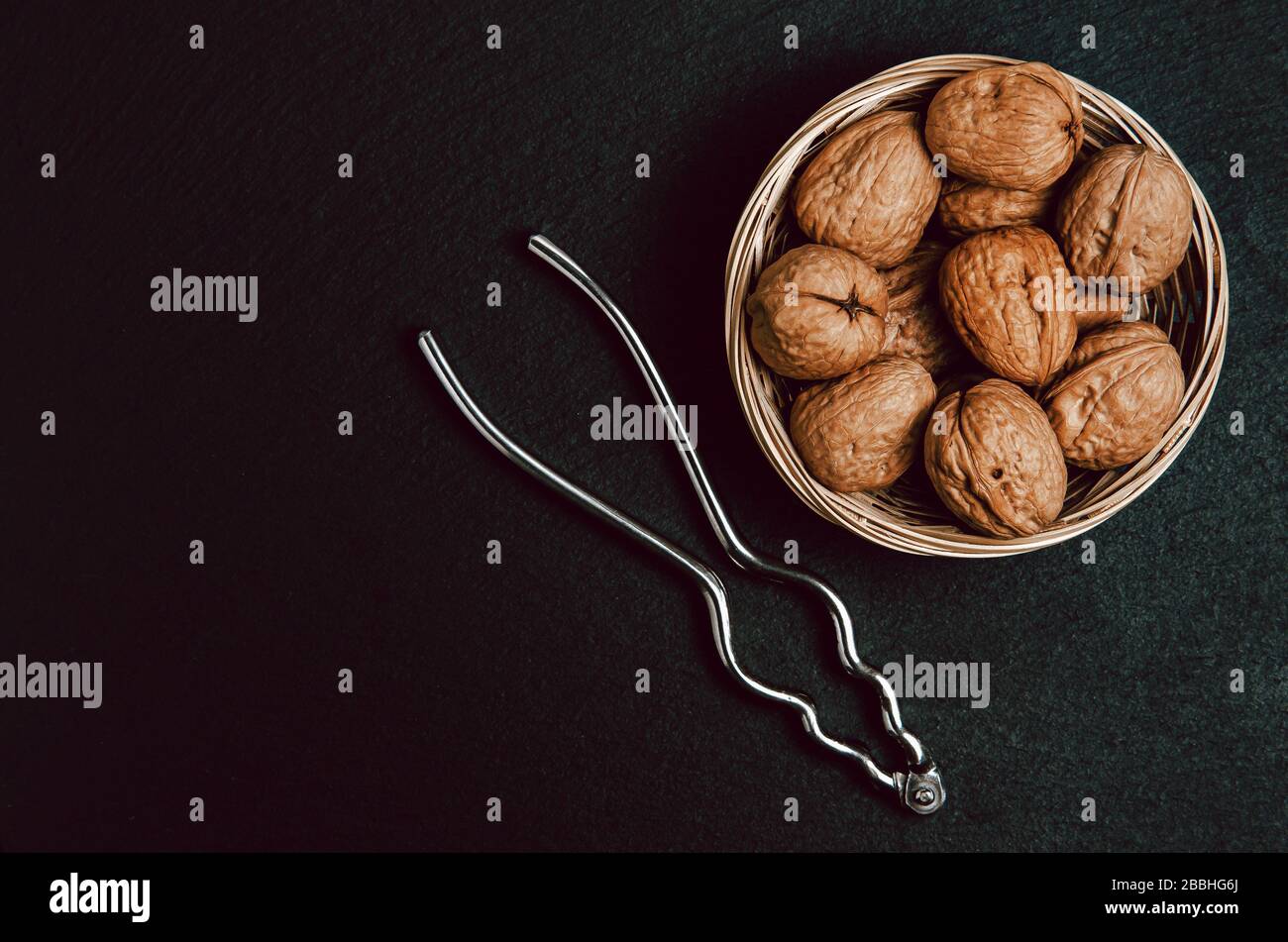 Walnuts with nutcracker on black background, top view. Stock Photo