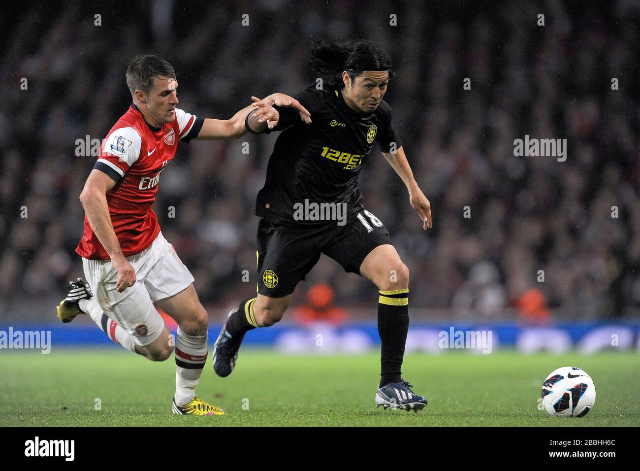 Arsenal's Aaron Ramsey and Wigan's Roger Espinoza fight for the ball. Stock Photo