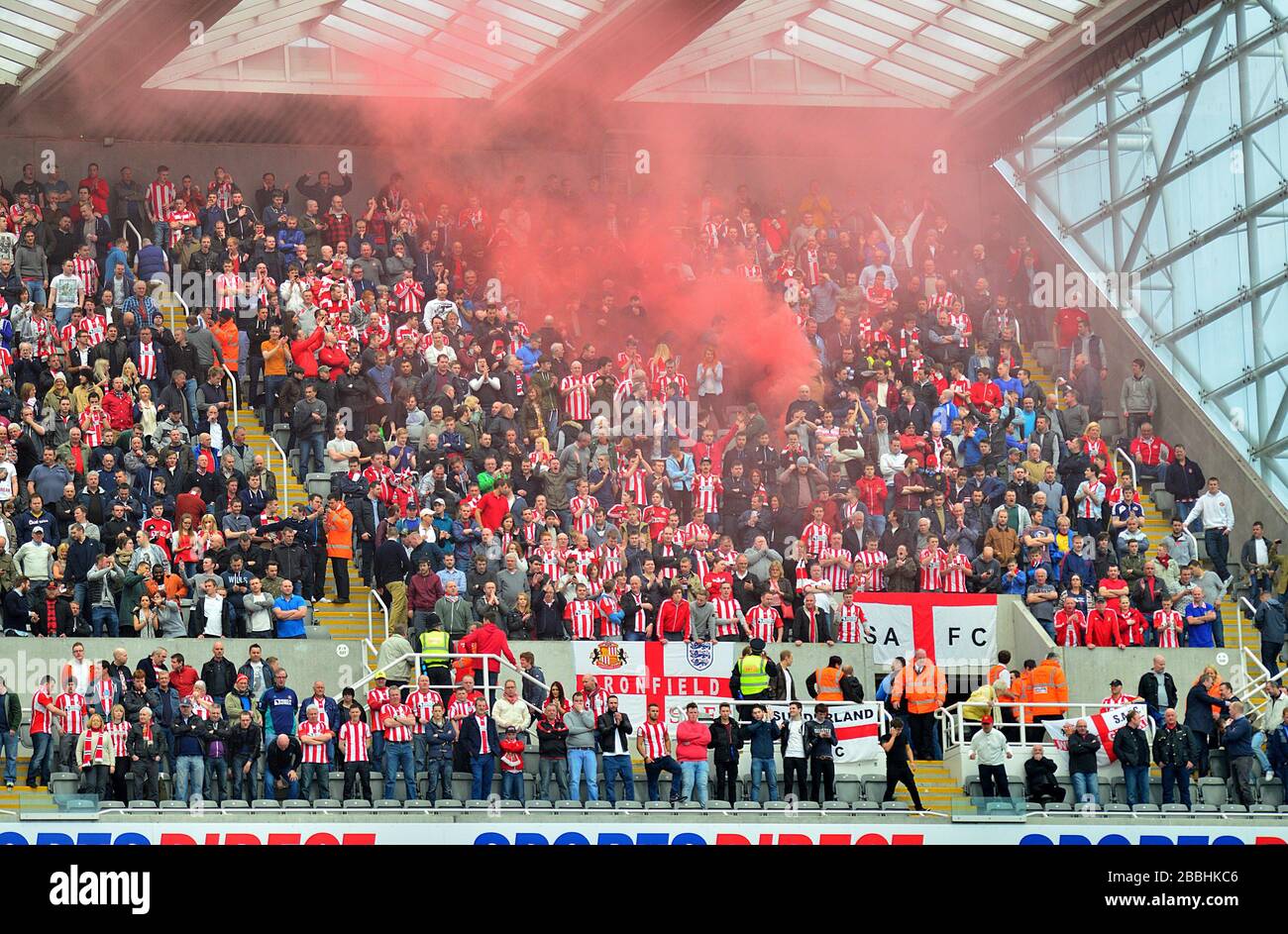 Red smoke drifts up above the Sunderland fans as they cheer on their side in the stands Stock Photo