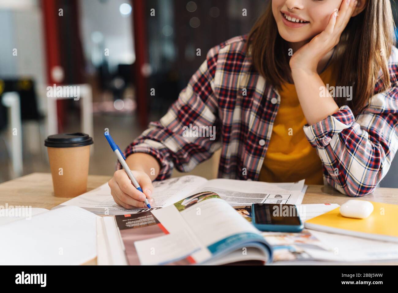 Cropped image of pleased caucasian girl doing homework with exercise ...