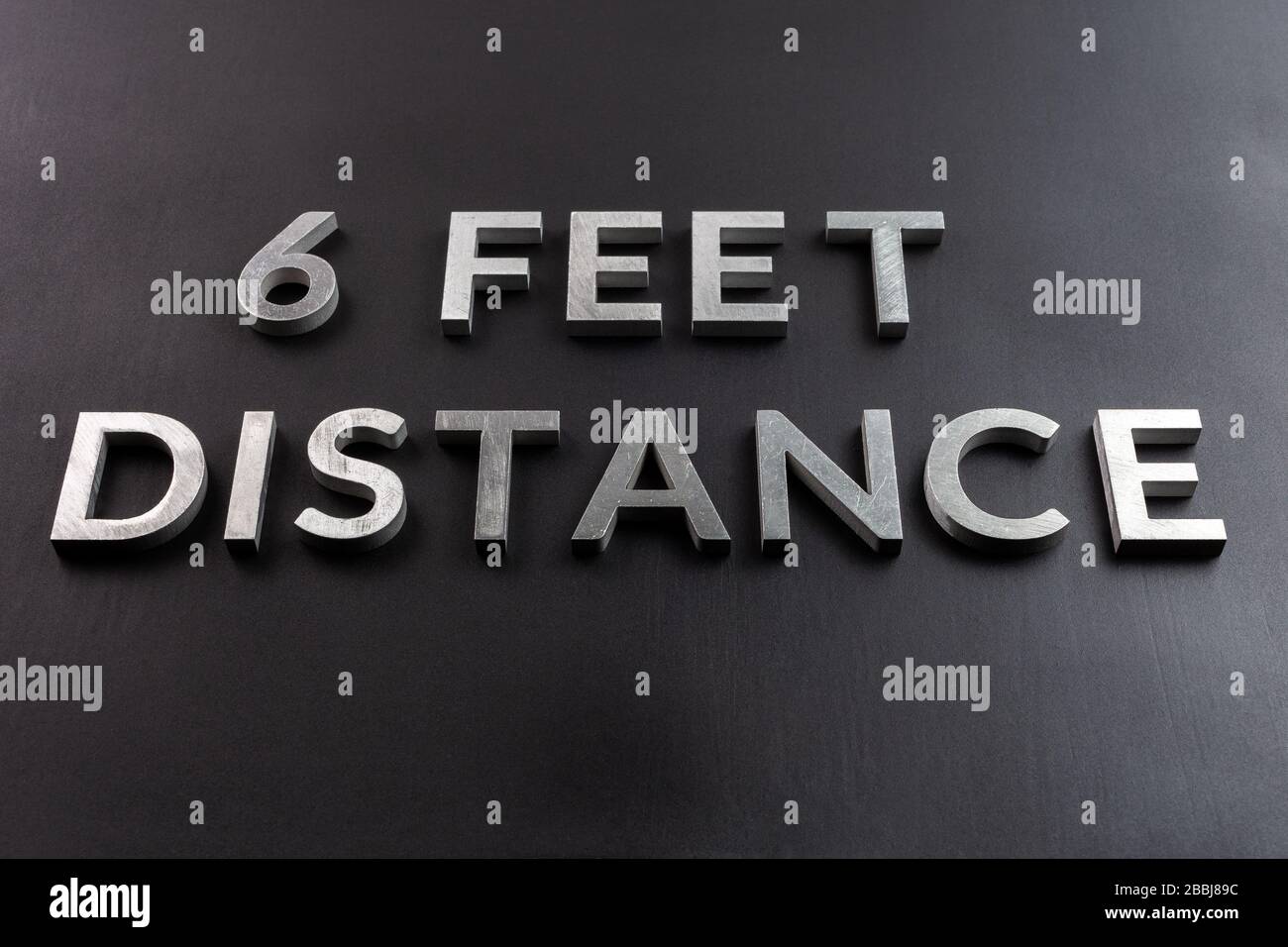 the words 6 feet distance laid with white metal letters on black matte surface in perspective composition and selective focus Stock Photo