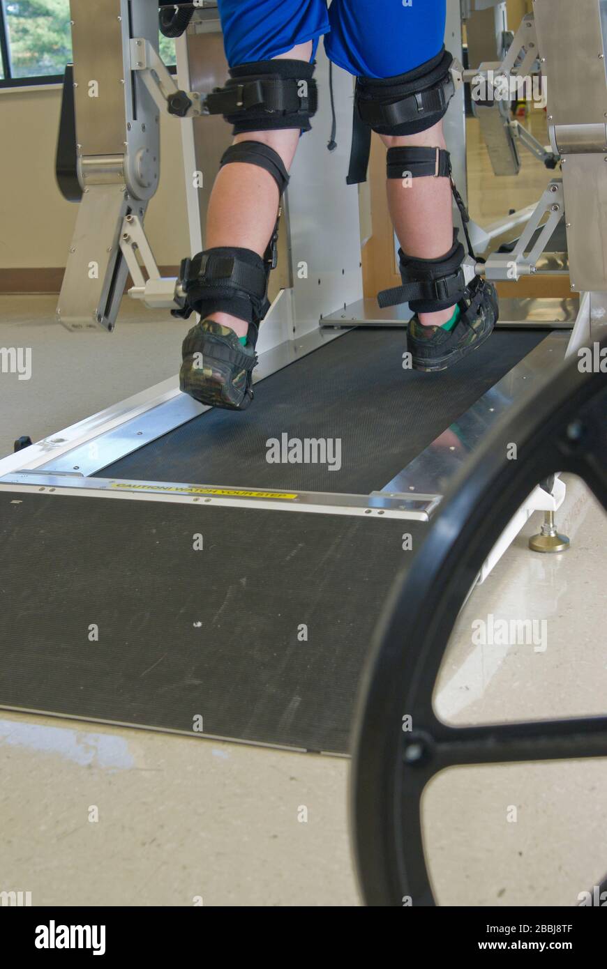Partial view of a man in physical therapy on a machine that assists paralyzed legs into walking motion Stock Photo