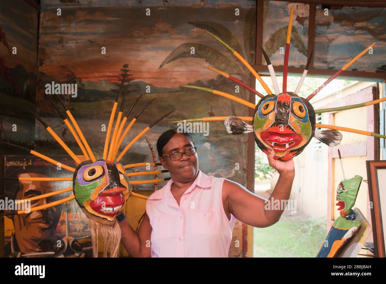 Woman holds a couple of the famous masks that her brother created, Loiza, Puerto Rico, USA Stock Photo