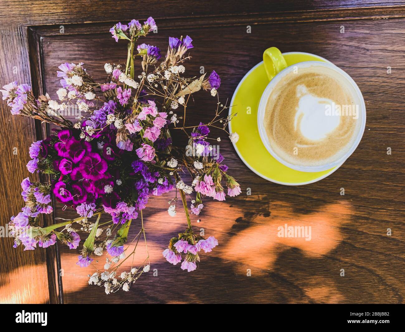 taza de cafe y postre sobre mesa de madera y flores Stock Photo