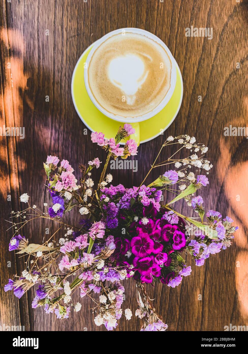 taza de cafe y postre sobre mesa de madera y flores Stock Photo