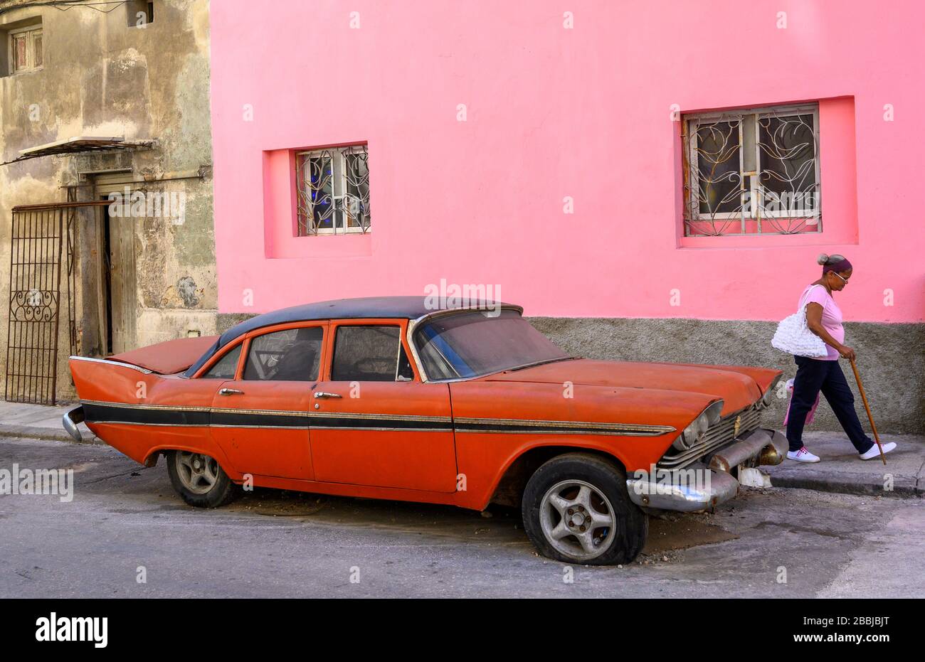 Pink wall with old red american fifties car, Centro, Havana, Cuba Stock Photo