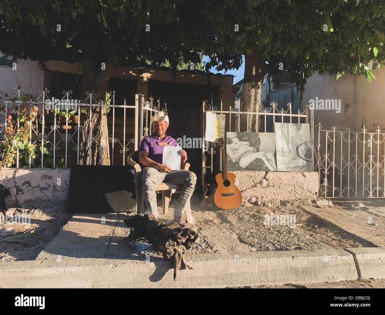 Un joven vaquero al amanecer con su fogata , dibujos y su guitarra en la acera de la colonia Progresista. Pelio Stock Photo