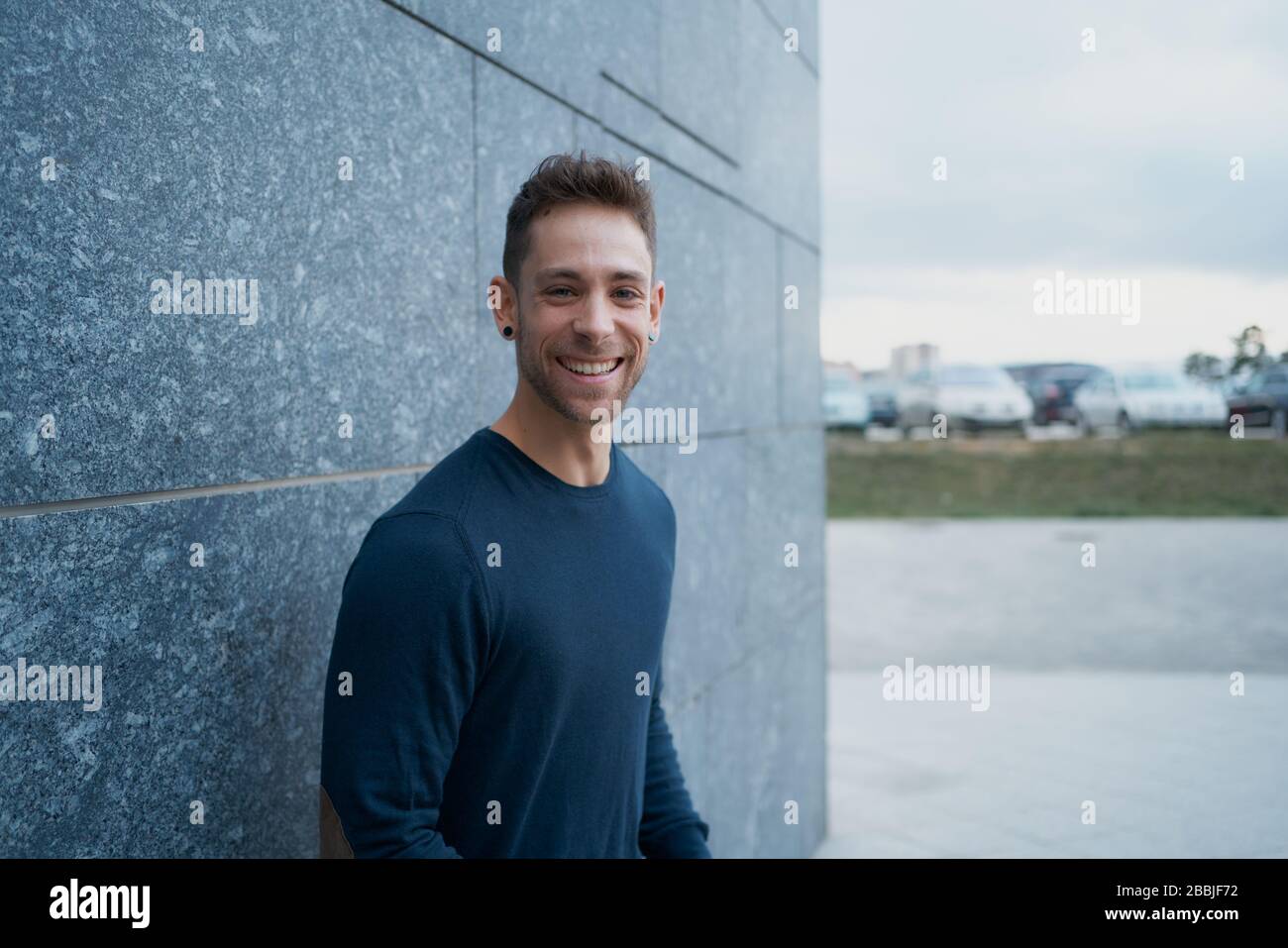 Side view of a modern man in casual clothes smiling straight at the st Stock Photo