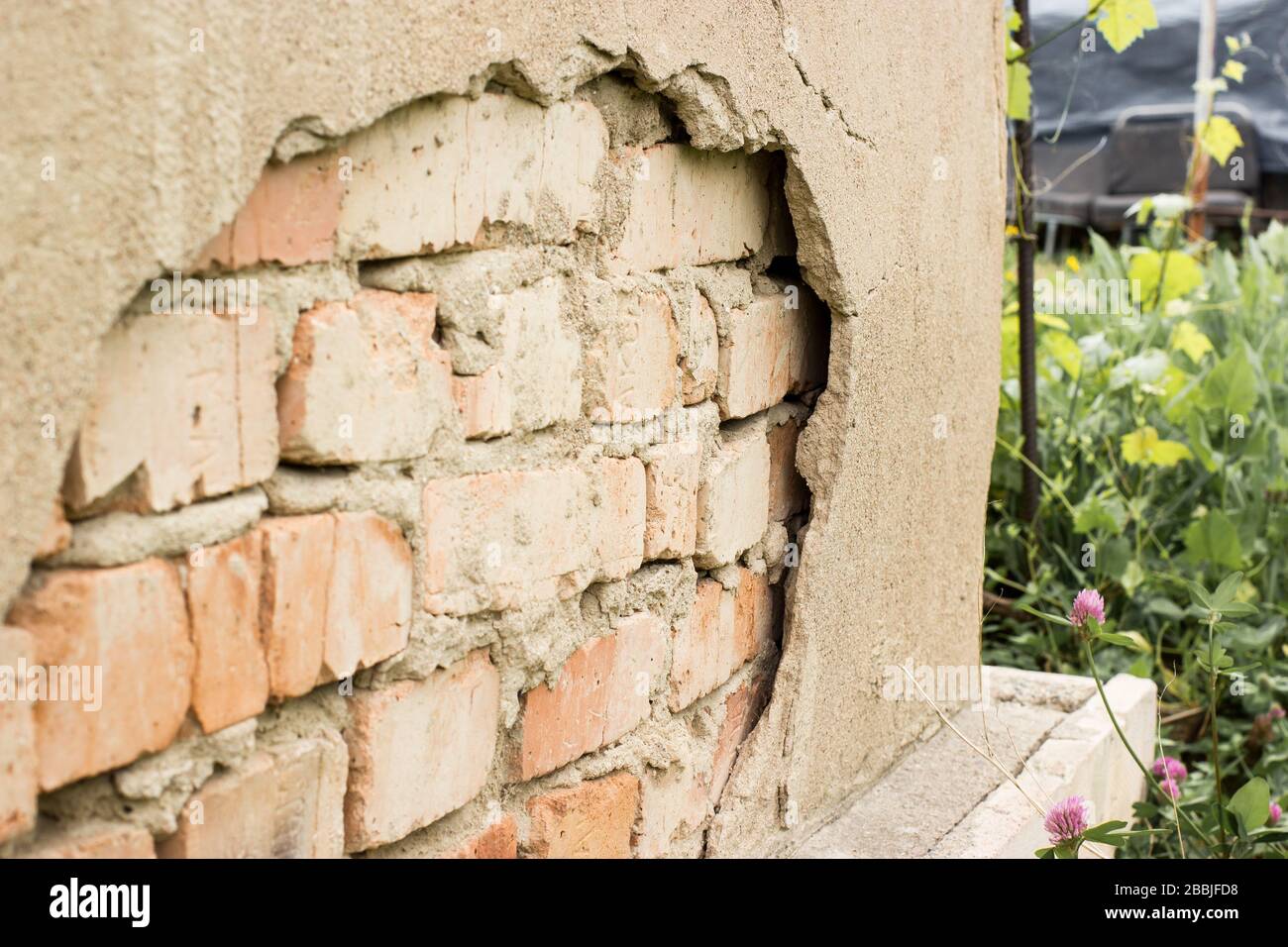 Non technology plaster. Building cracked plaster facade wall with brick. Stock Photo