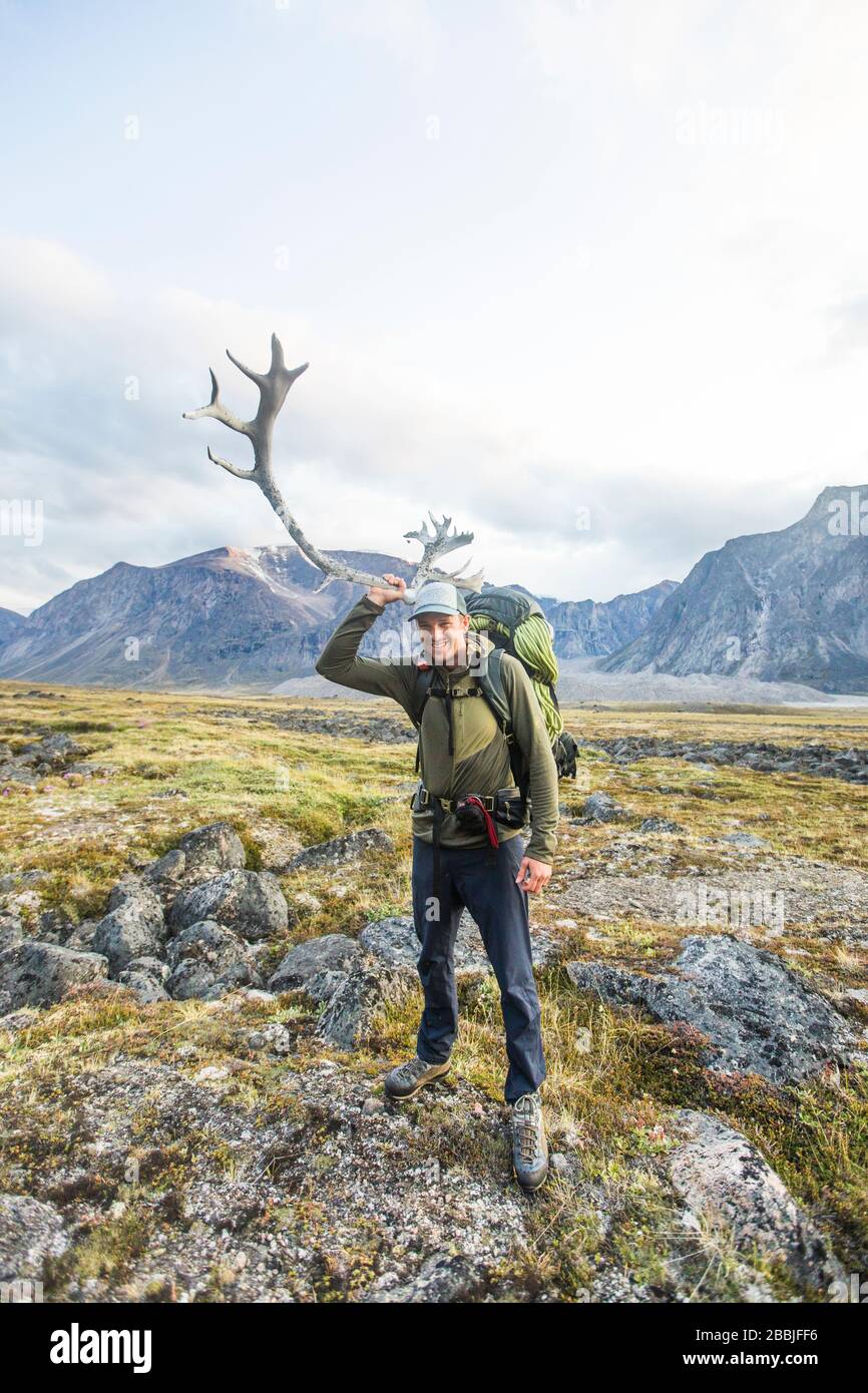 Backpacker holds up Caribou antler to his head on remote Baffin Island Stock Photo