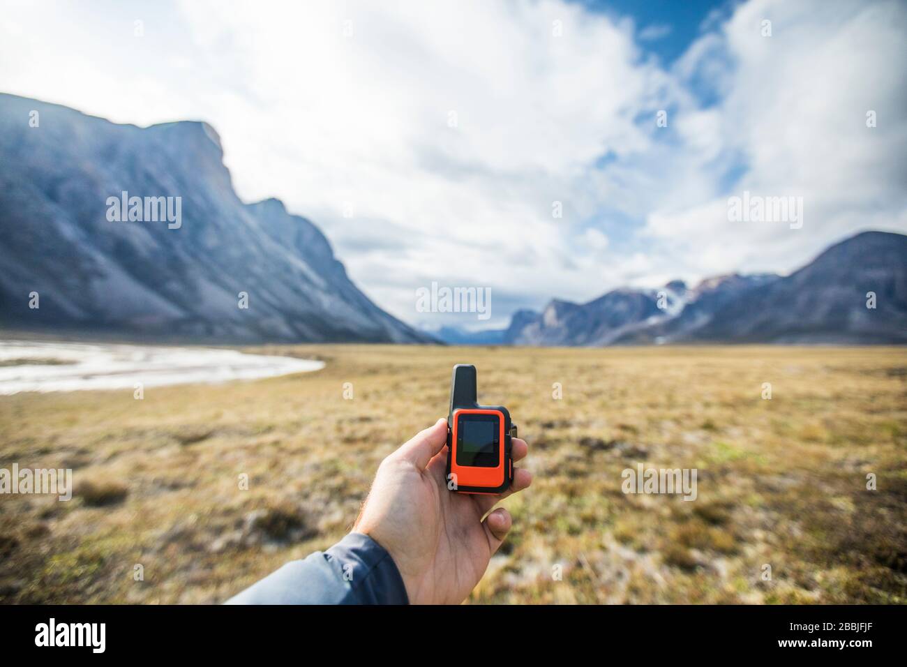 Adventurer holds mini GPS and satellite safety communication device. Stock Photo