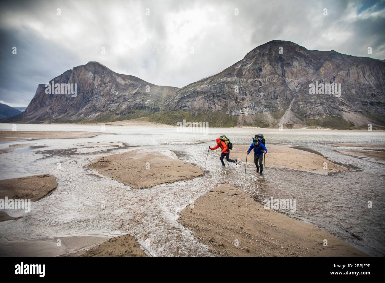 Two backpackers navigate a series of river crossings in Akshayak Pass Stock Photo