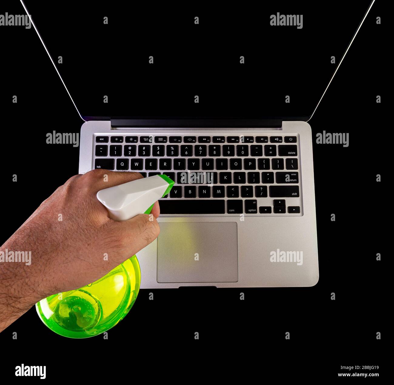 Hand cleaning a laptop with a spray bottle sanitizer Stock Photo Alamy