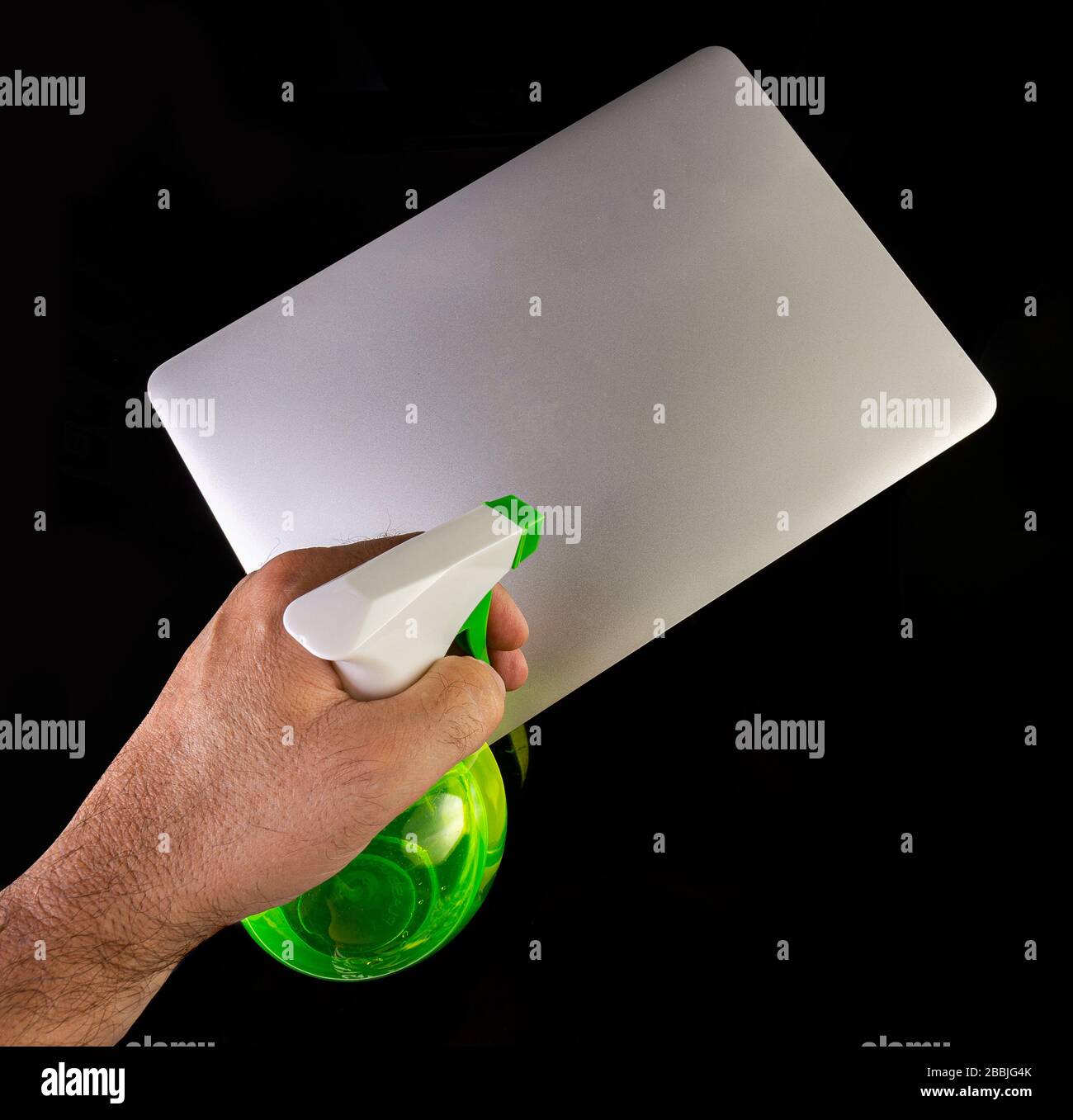 Hand cleaning a laptop with a spray bottle sanitizer Stock Photo Alamy
