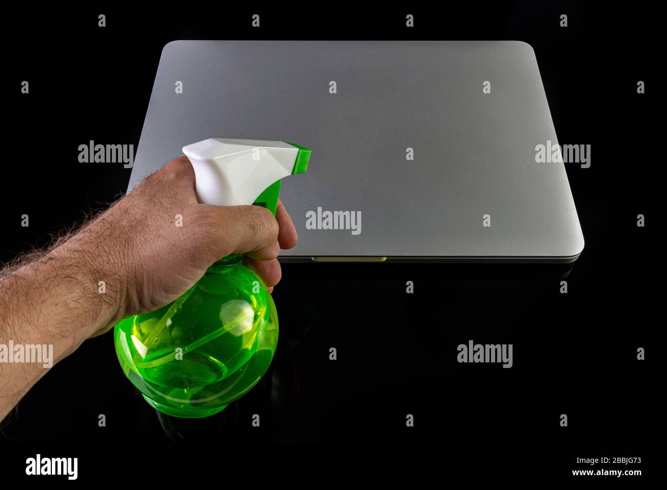 Hand cleaning a laptop with a spray bottle sanitizer Stock Photo Alamy