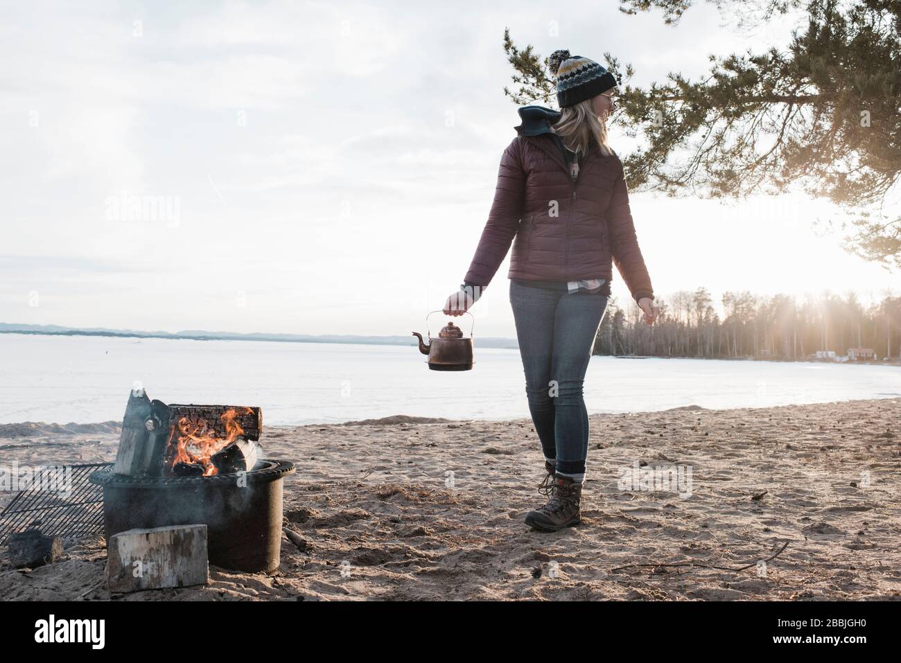 woman walking with kettle to a campfire on a beach  in Sweden Stock Photo
