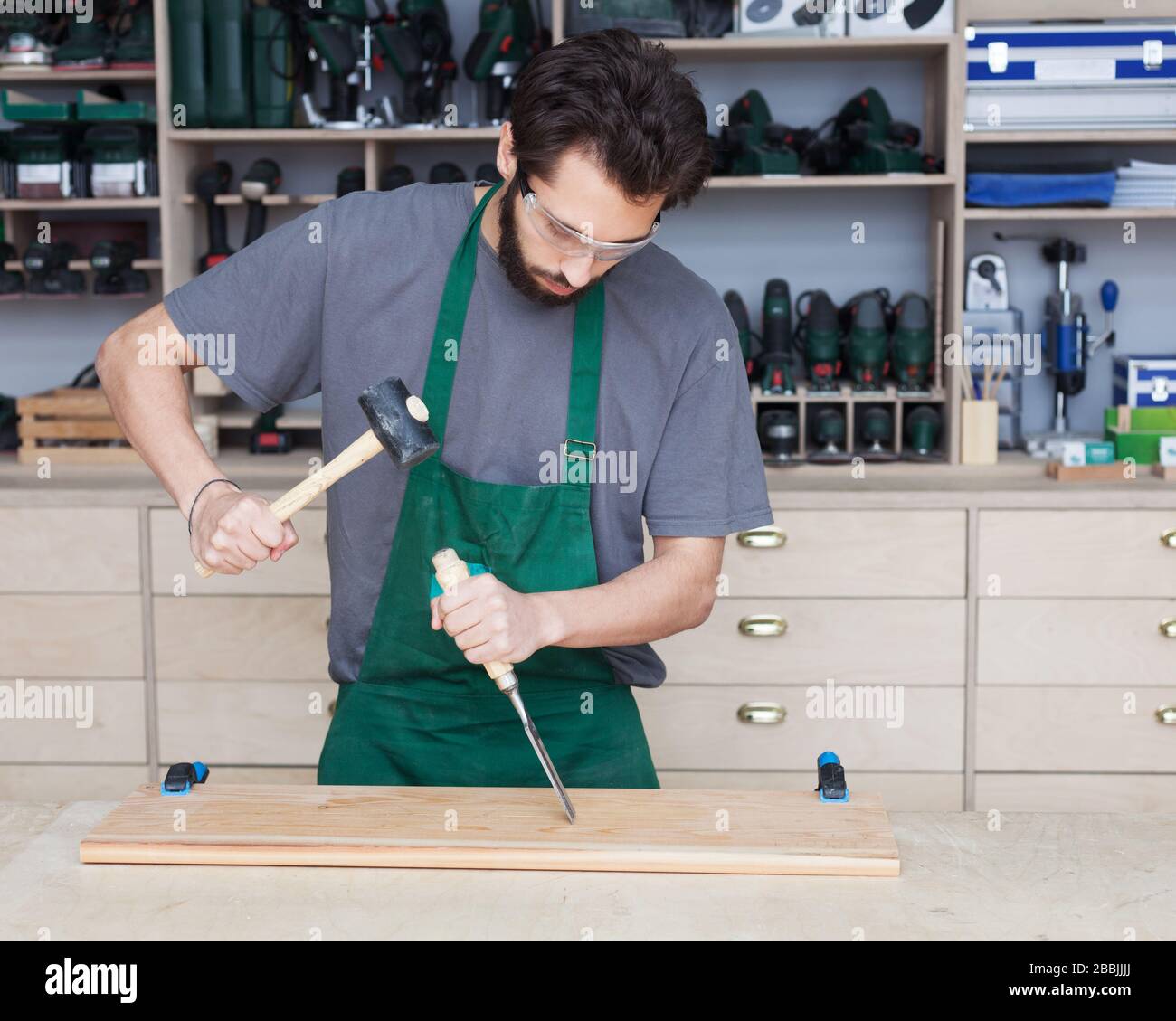 Carpenter with chisel in the hands on the workbench in carpentry workshop Stock Photo