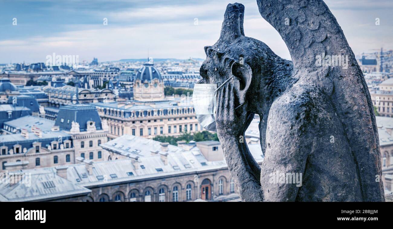 COVID-19 coronavirus in France, medical mask on gargoyle of Notre Dame in Paris. Tourist landmarks closed due to corona virus outbreak. Concept of tra Stock Photo