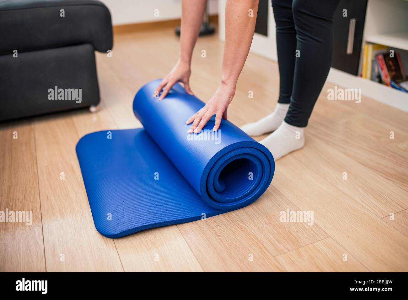 Close-up of a woman unrolling the yoga mat to exercise at home. Stock Photo