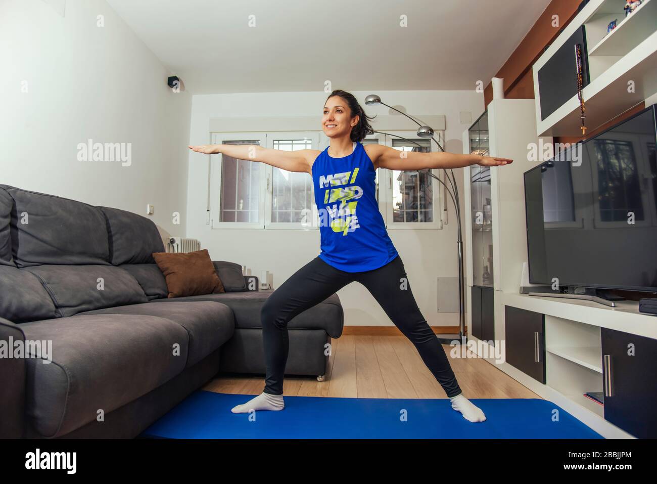 Young woman doing a yoga pose called the warrior at home Stock Photo