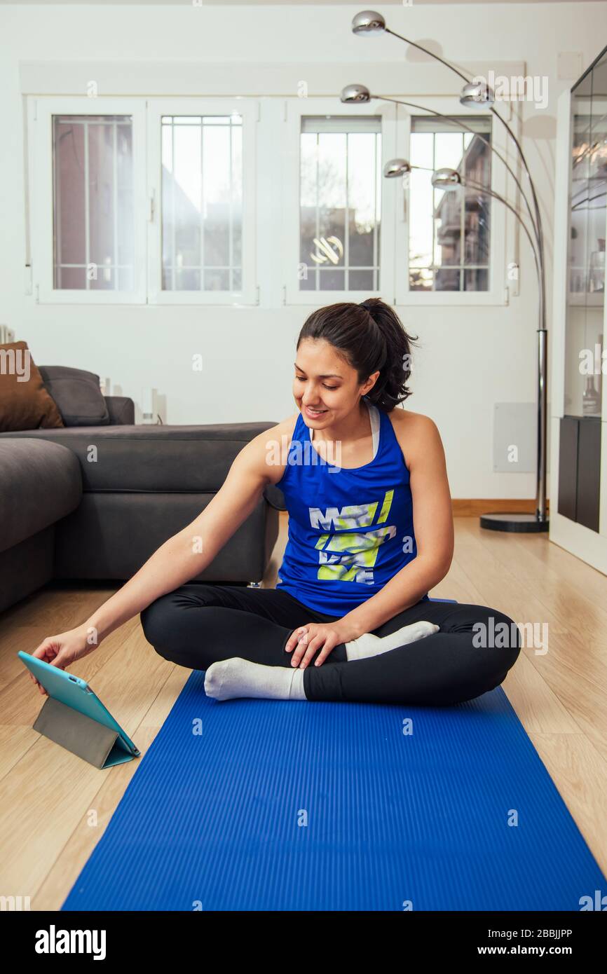 woman practicing yoga at home, watching an online yoga class from her tablet Stock Photo