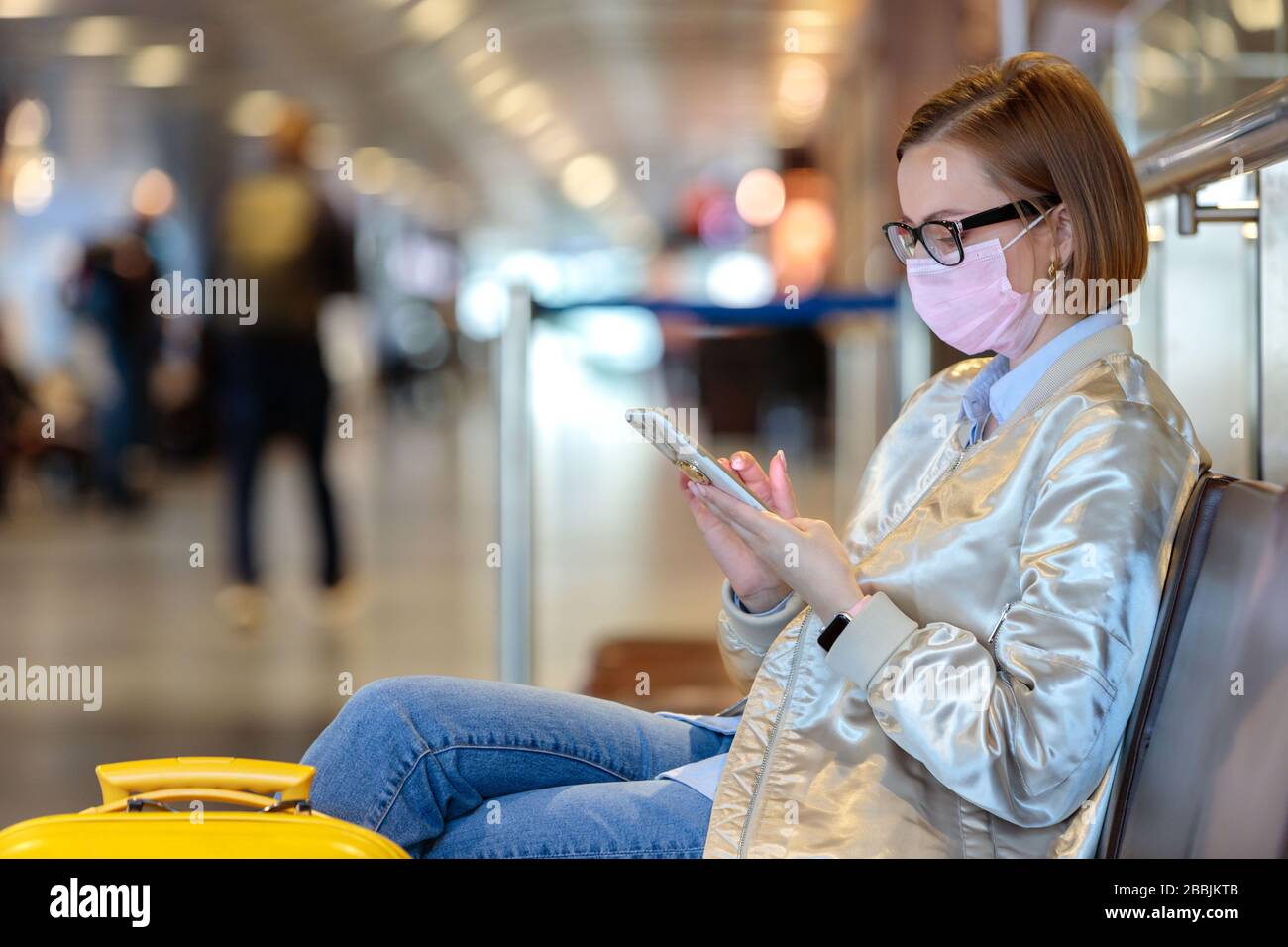 Woman upset over flight cancellation, writes message to family, sitting in almost empty airport terminal due to coronavirus pandemic/Covid-19 outbreak Stock Photo