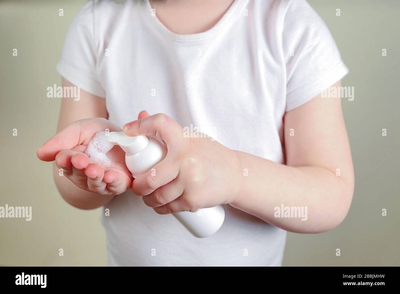 Child applying foam sanitizer on her hands. Stock Photo