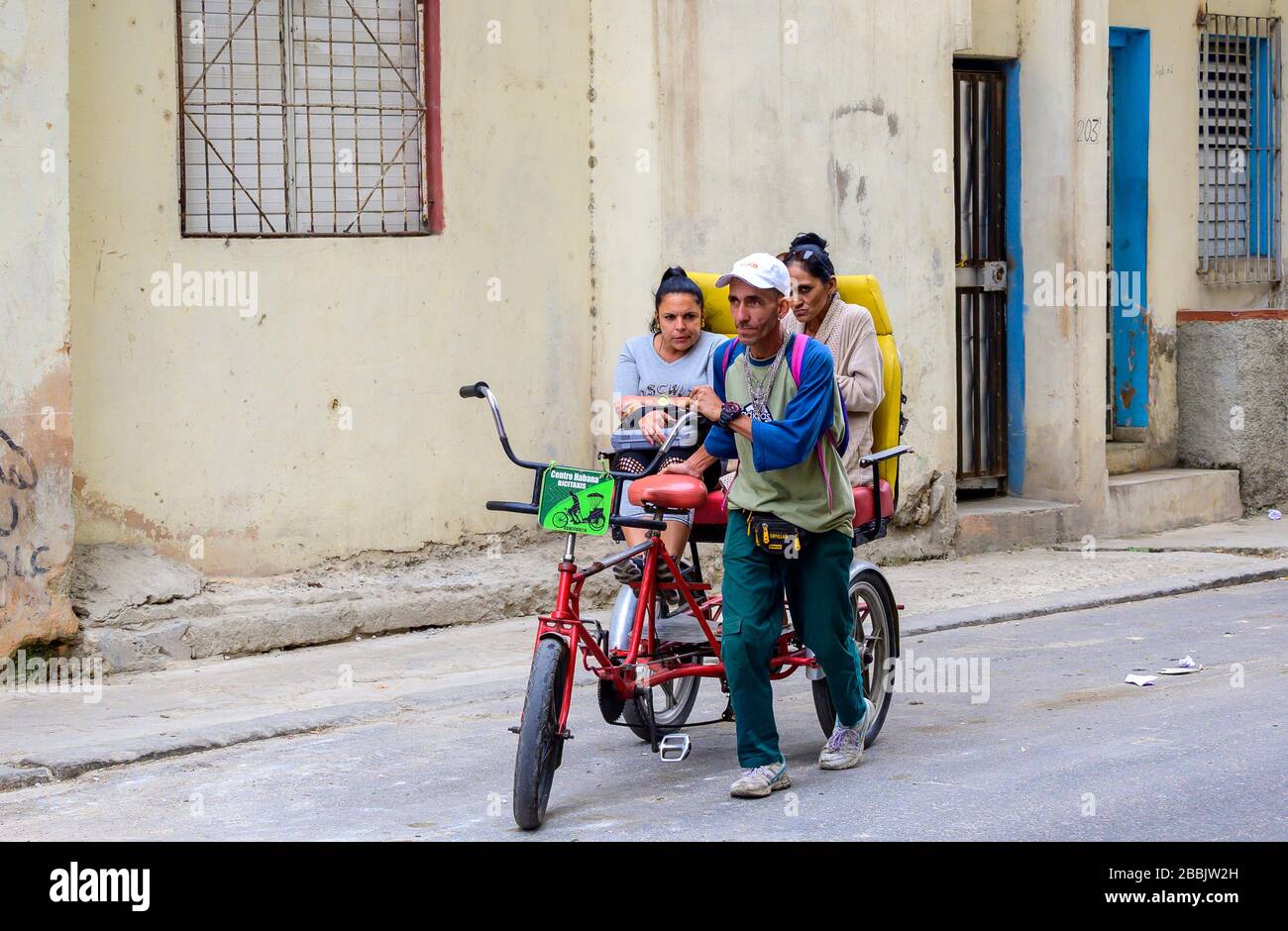 Man wheels two women in bicitaxi, Havana  Centro, Cuba Stock Photo