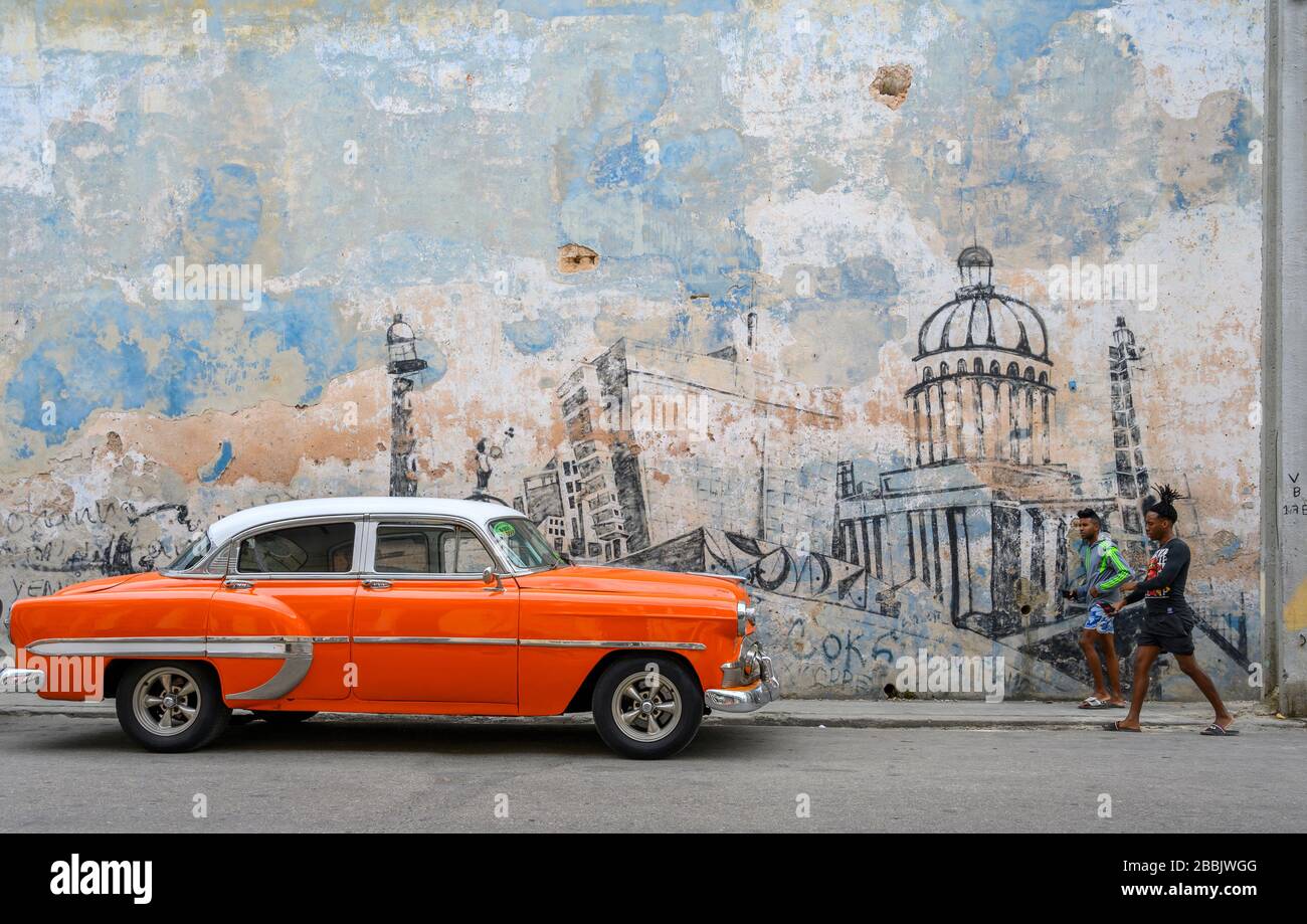 Old American Cars and wall mural of Havana, Cuba Stock Photo