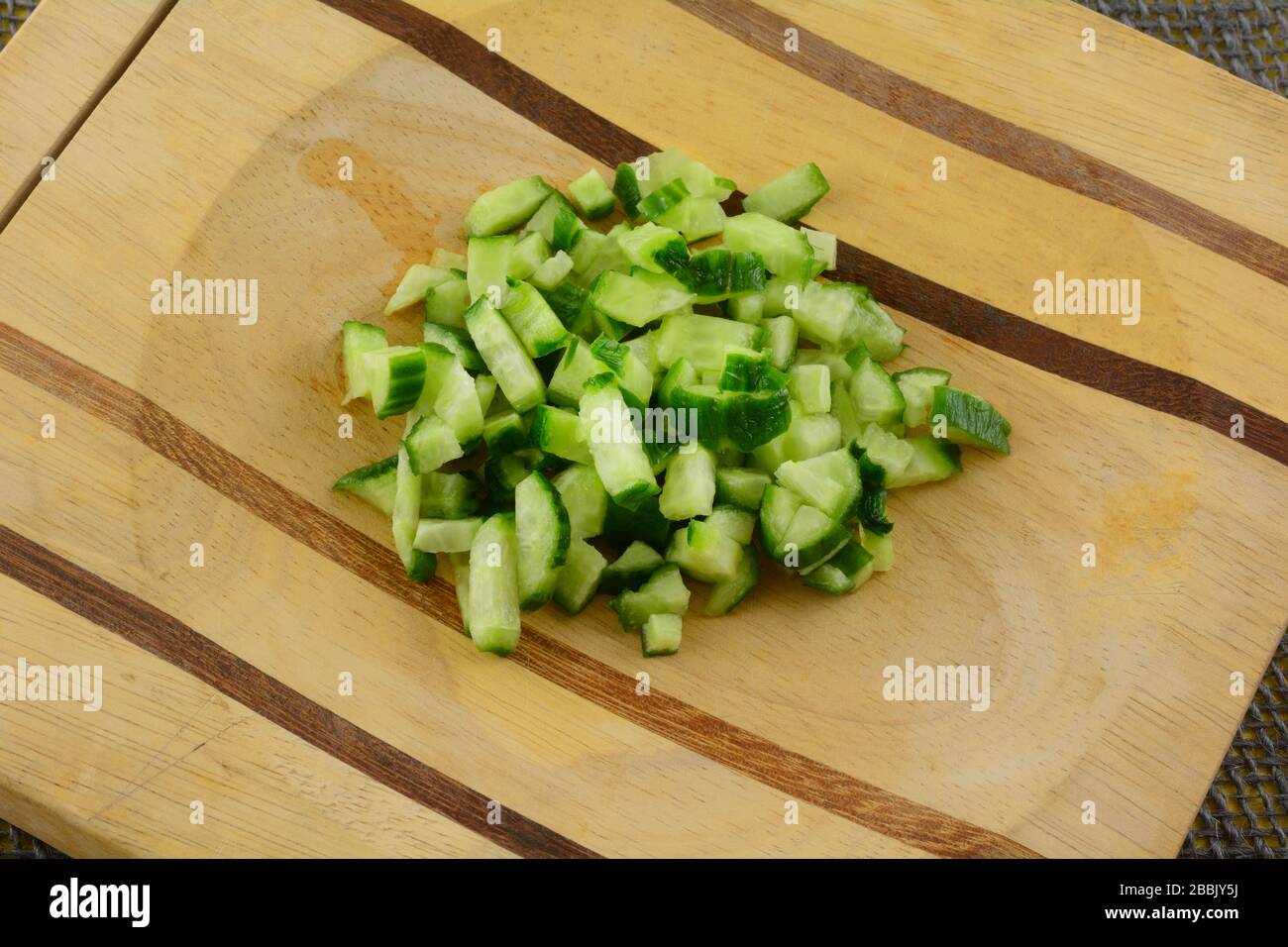 Close up of chopped fresh raw Persian cucumber on wooden cutting board Stock Photo