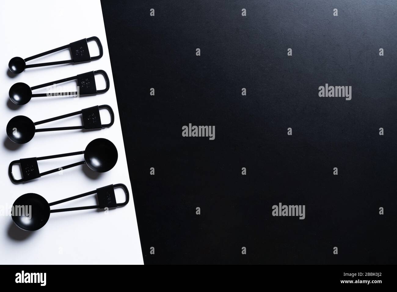 https://c8.alamy.com/comp/2BBK0J2/black-measuring-spoons-on-black-and-white-background-2BBK0J2.jpg