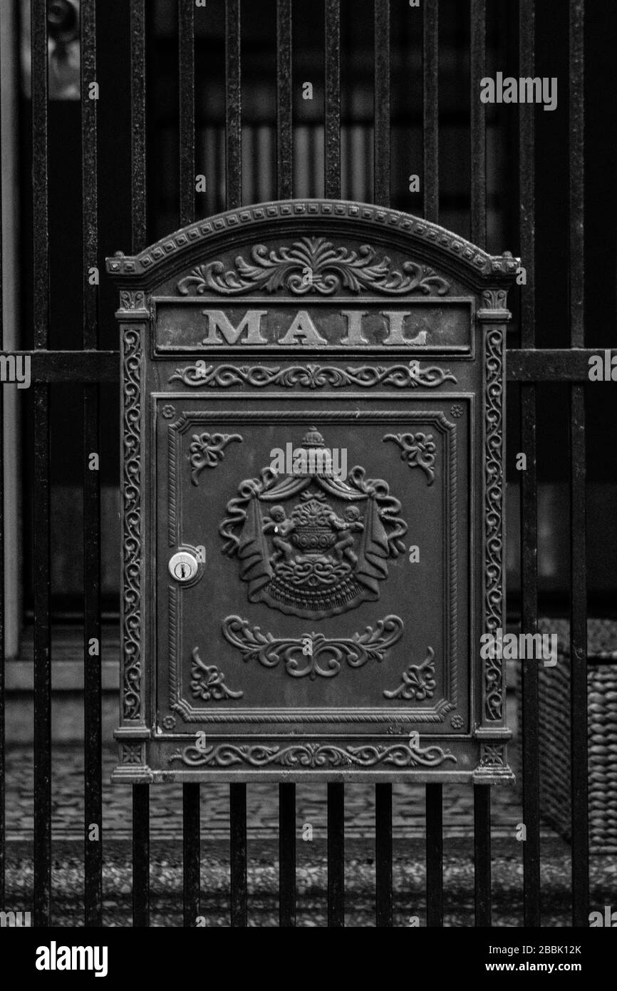 An antique mailbox on an iron fence Stock Photo