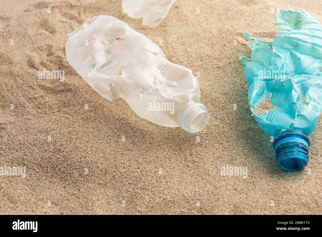 Plastic bottle lies on the beach and pollutes the sea. Spilled garbage on the beach. Empty used dirty plastic Stock Photo