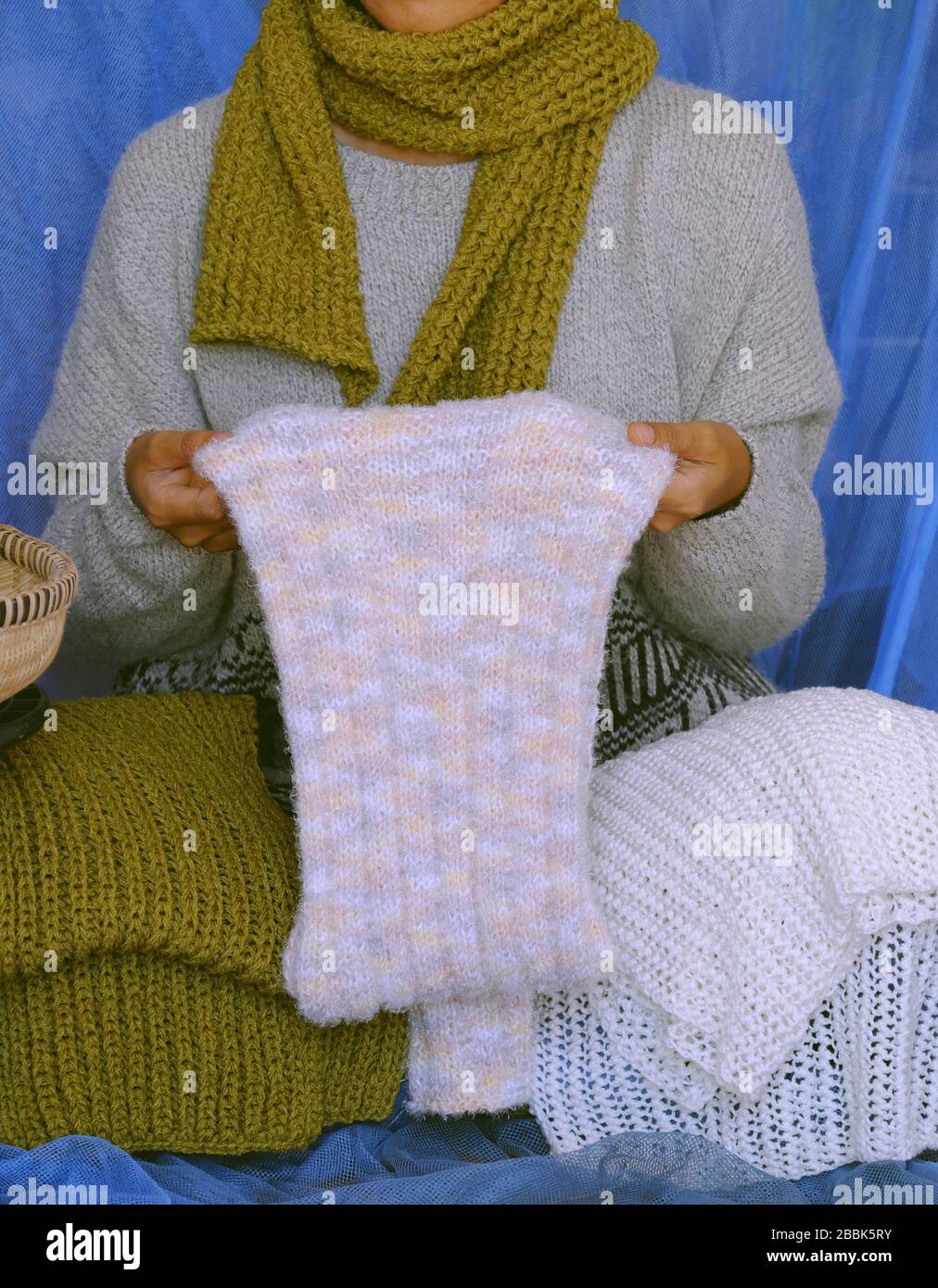 Concept with woman wear blue jeans, white woolen sweater, sock, white and moss green wool scarf on blue background, knitted handmade product to make w Stock Photo
