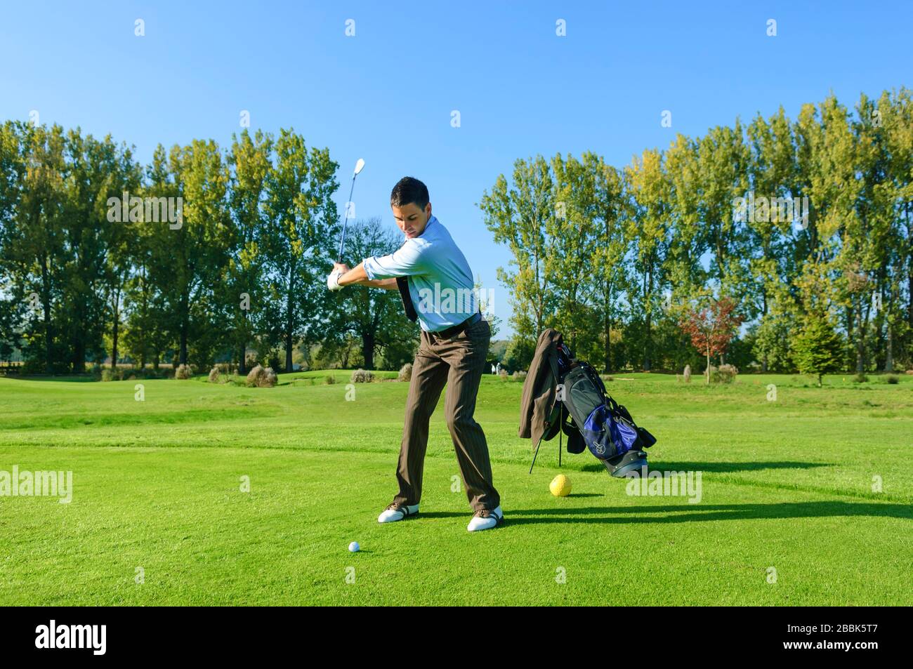 Man in business outfit playing golf in the afternoon Stock Photo - Alamy