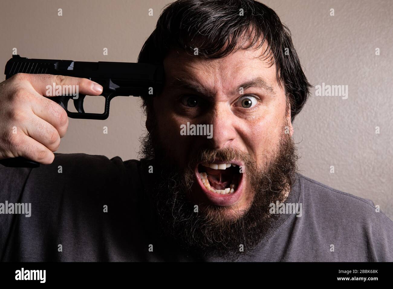 Desperate man screams before comitting suicide by pulling the trigger Stock Photo